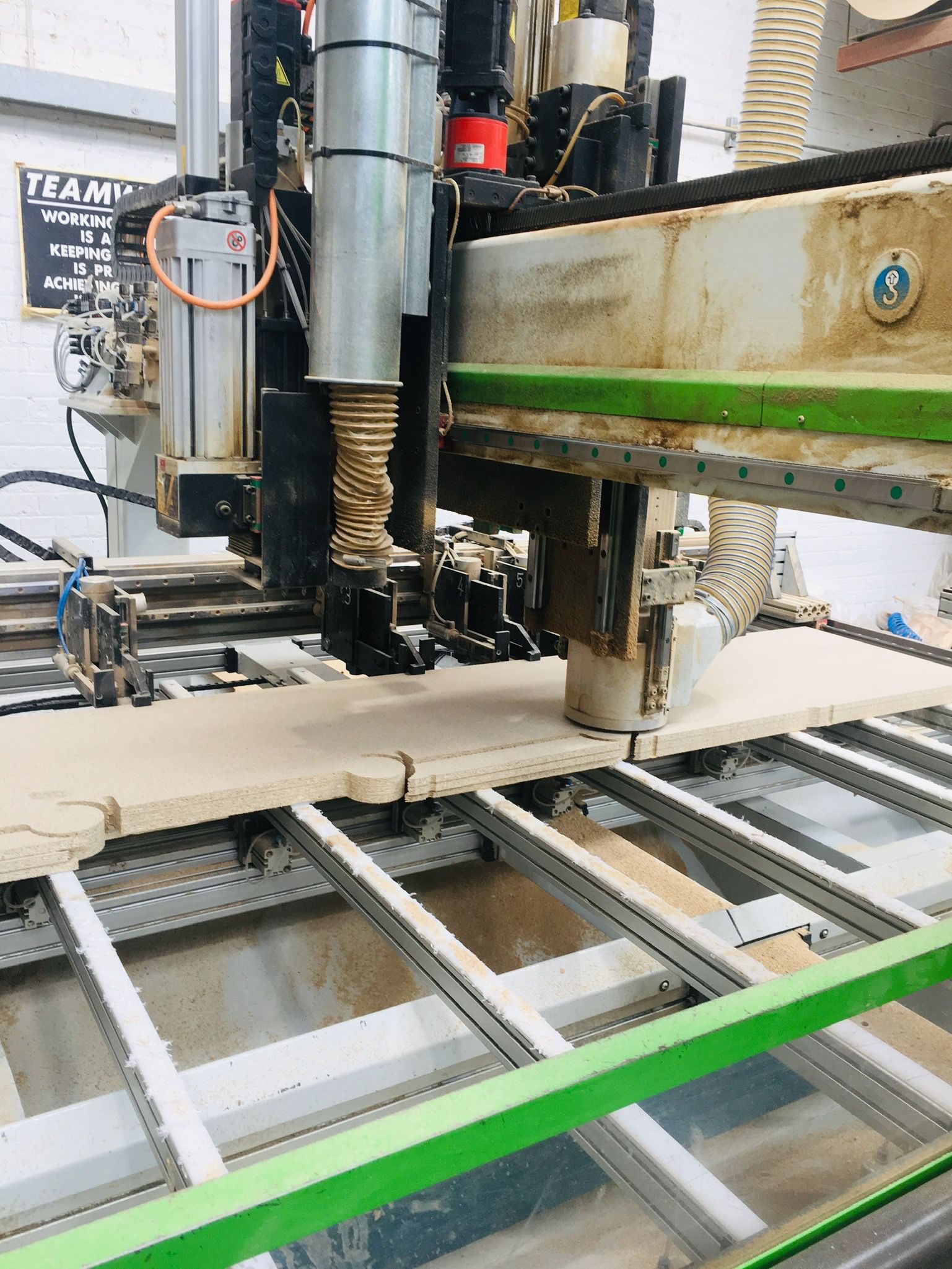 A CNC machine cutting sofa frame parts from board