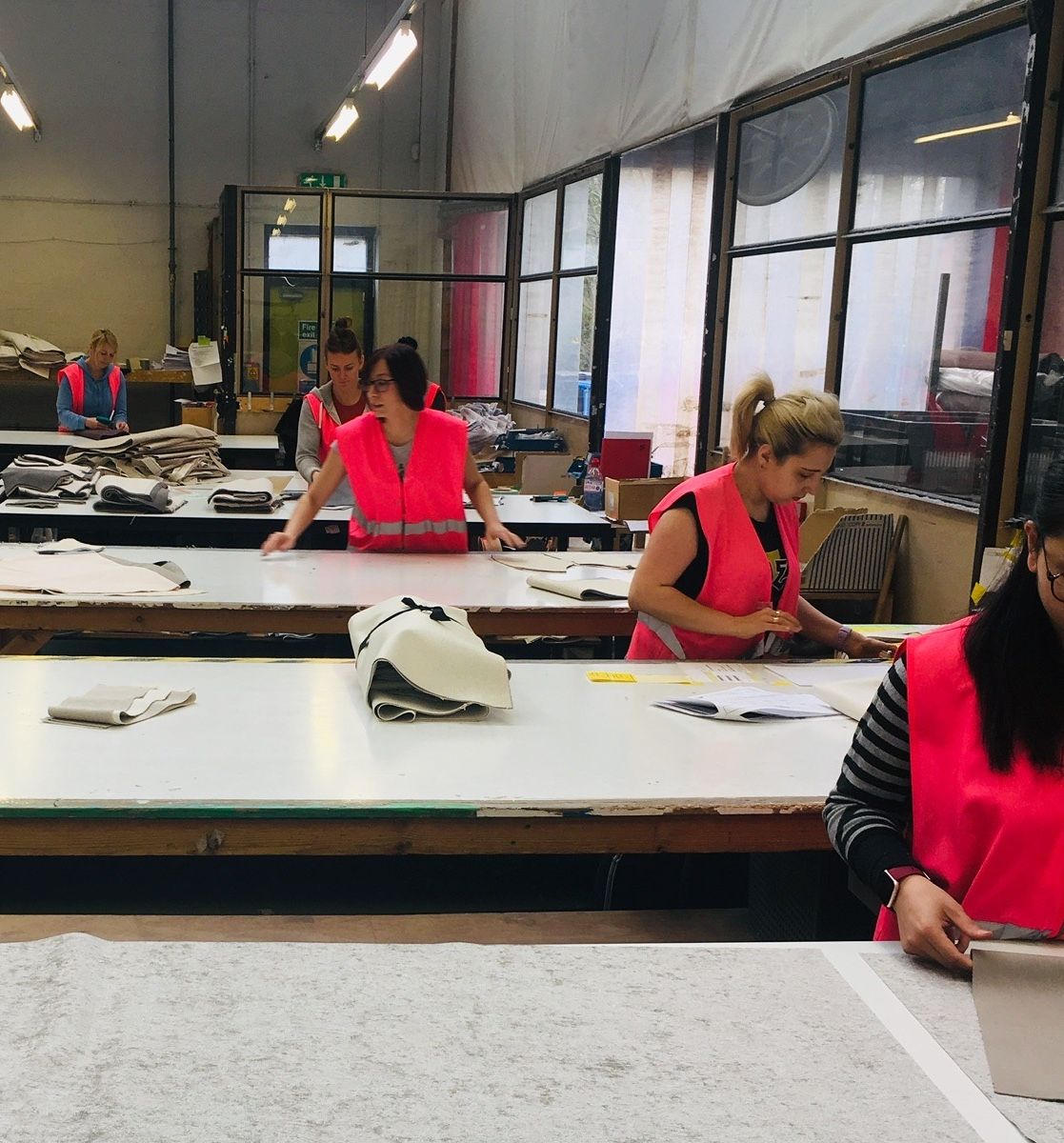 Staff in hi-vis cutting fabric templates on a long table